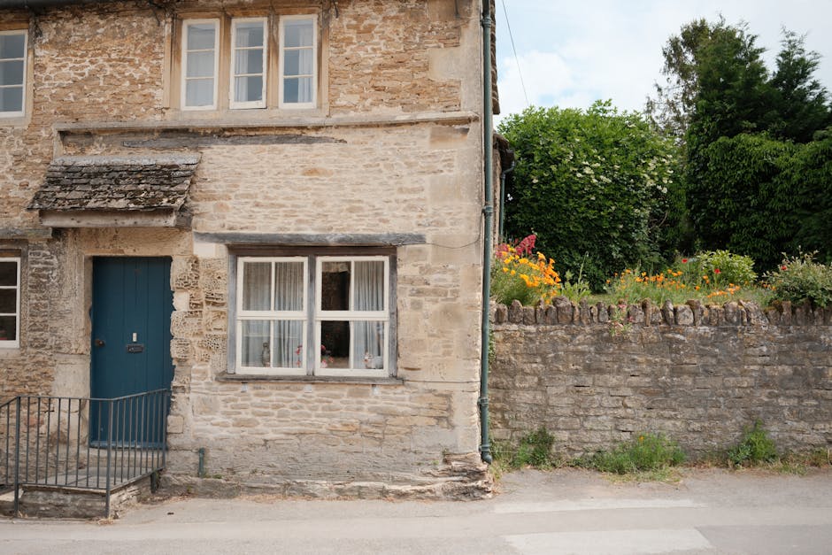 Cottage di pietra con porta blu e muro fiorito in un villaggio inglese